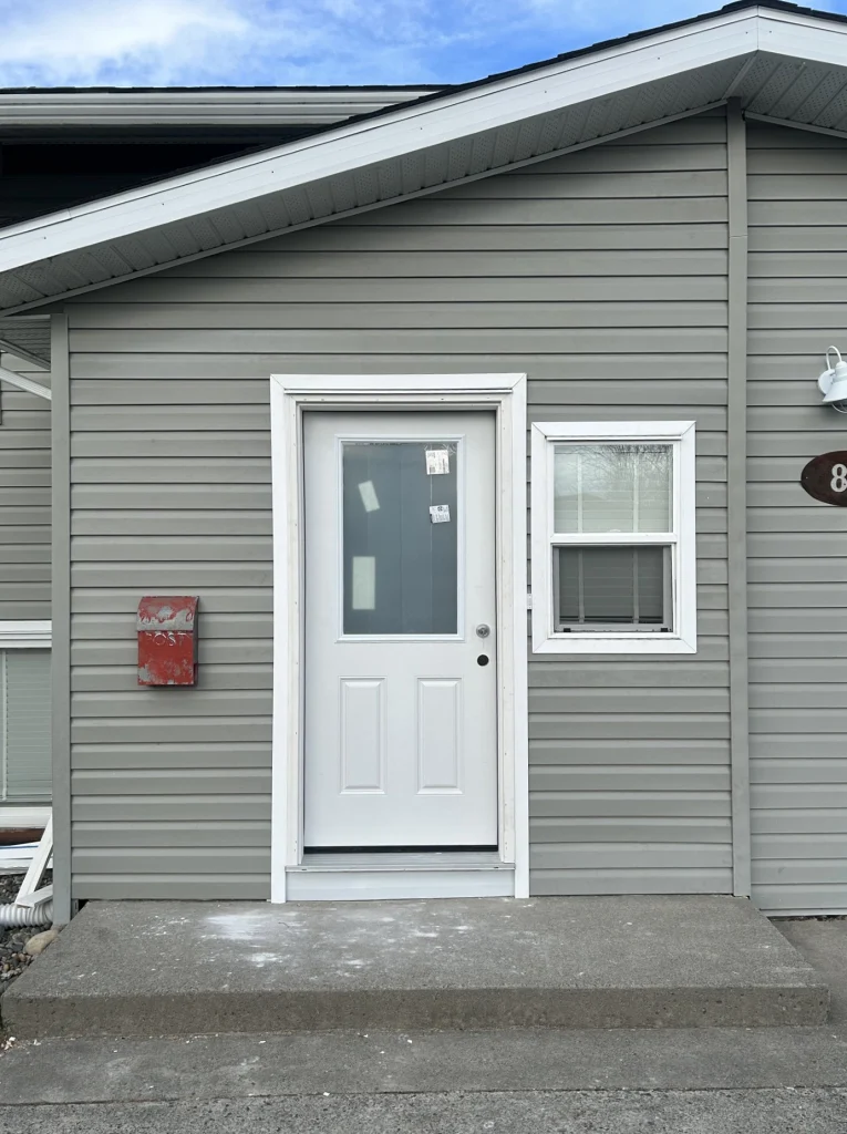 Completed exterior entry renovation with new siding, trim, and door installation