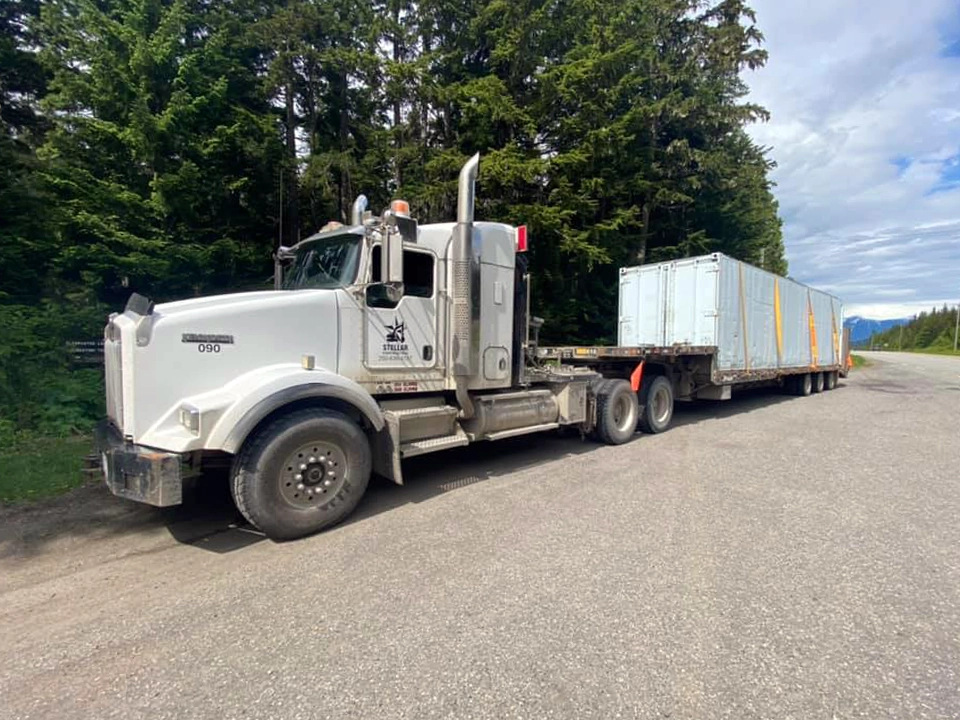 White transport truck hauling a storage container
